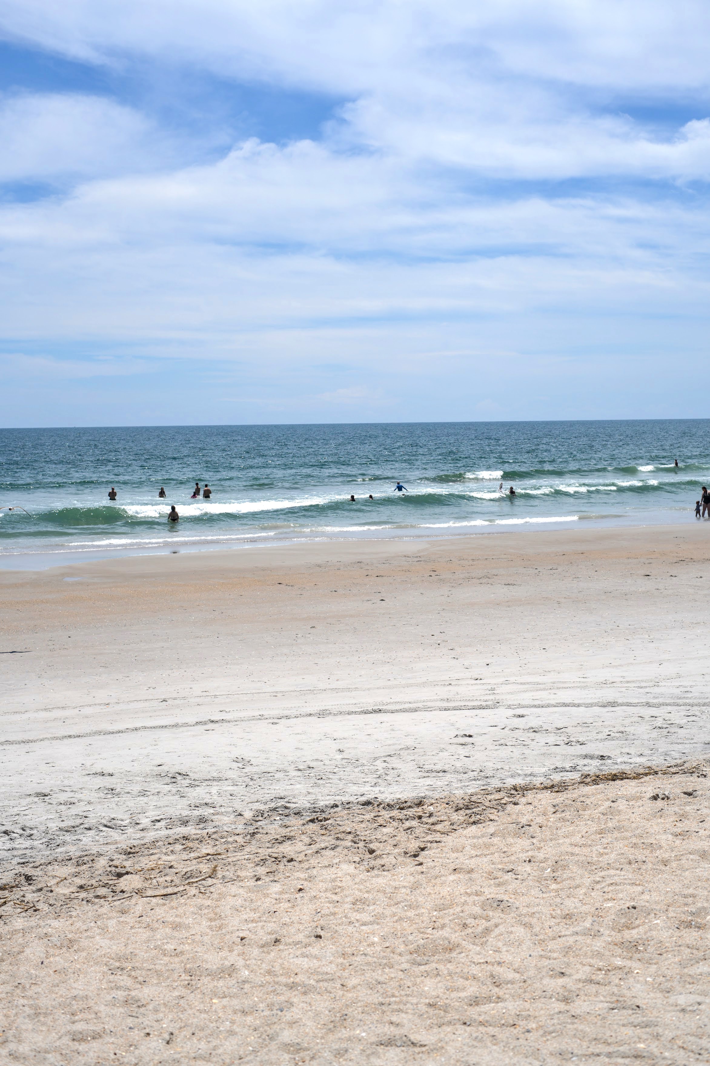 Gentle waves and swimmers along the sandy Atlantic shoreline at Wrightsville Beach, NC.