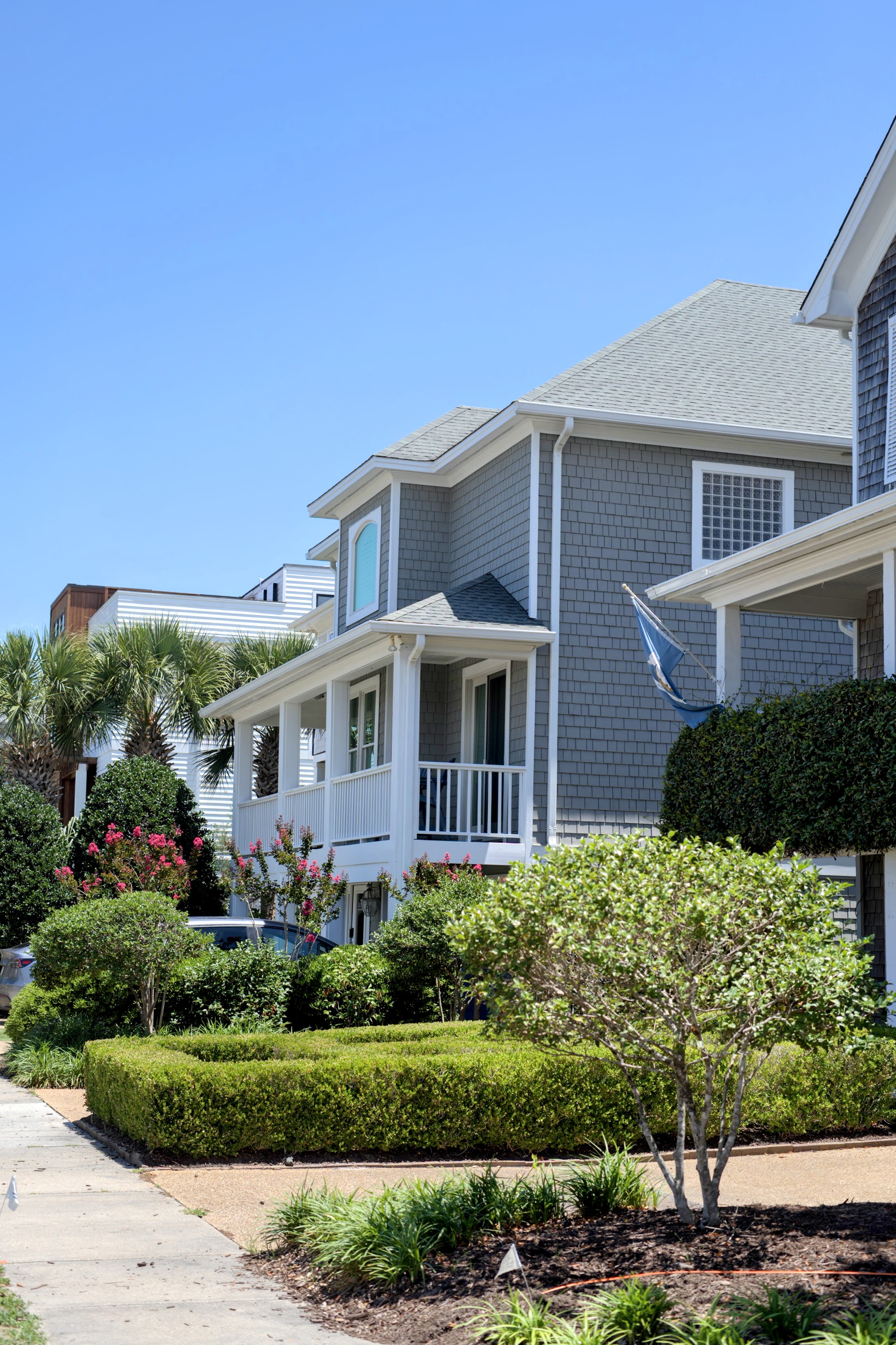 Gray shingled coastal home with white porches and tidy landscaping in Wrightsville Beach, NC.