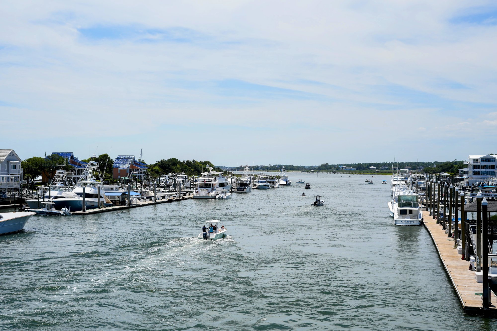 Boats cruising the Intracoastal Waterway past marinas and waterfront homes in Wrightsville Beach, NC.