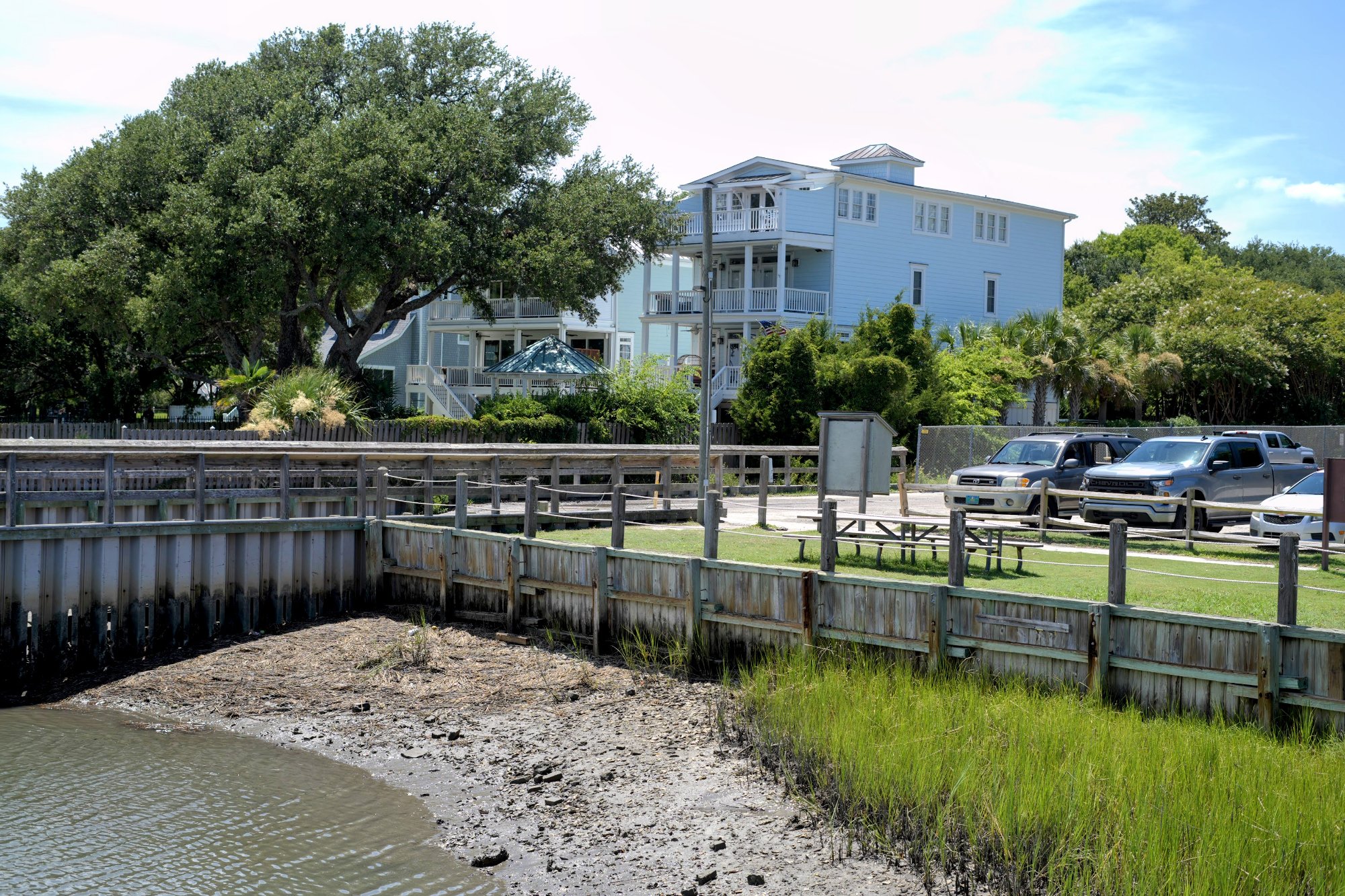 Waterfront homes and a boardwalk overlooking a marsh cove at low tide in Wrightsville Beach, NC.