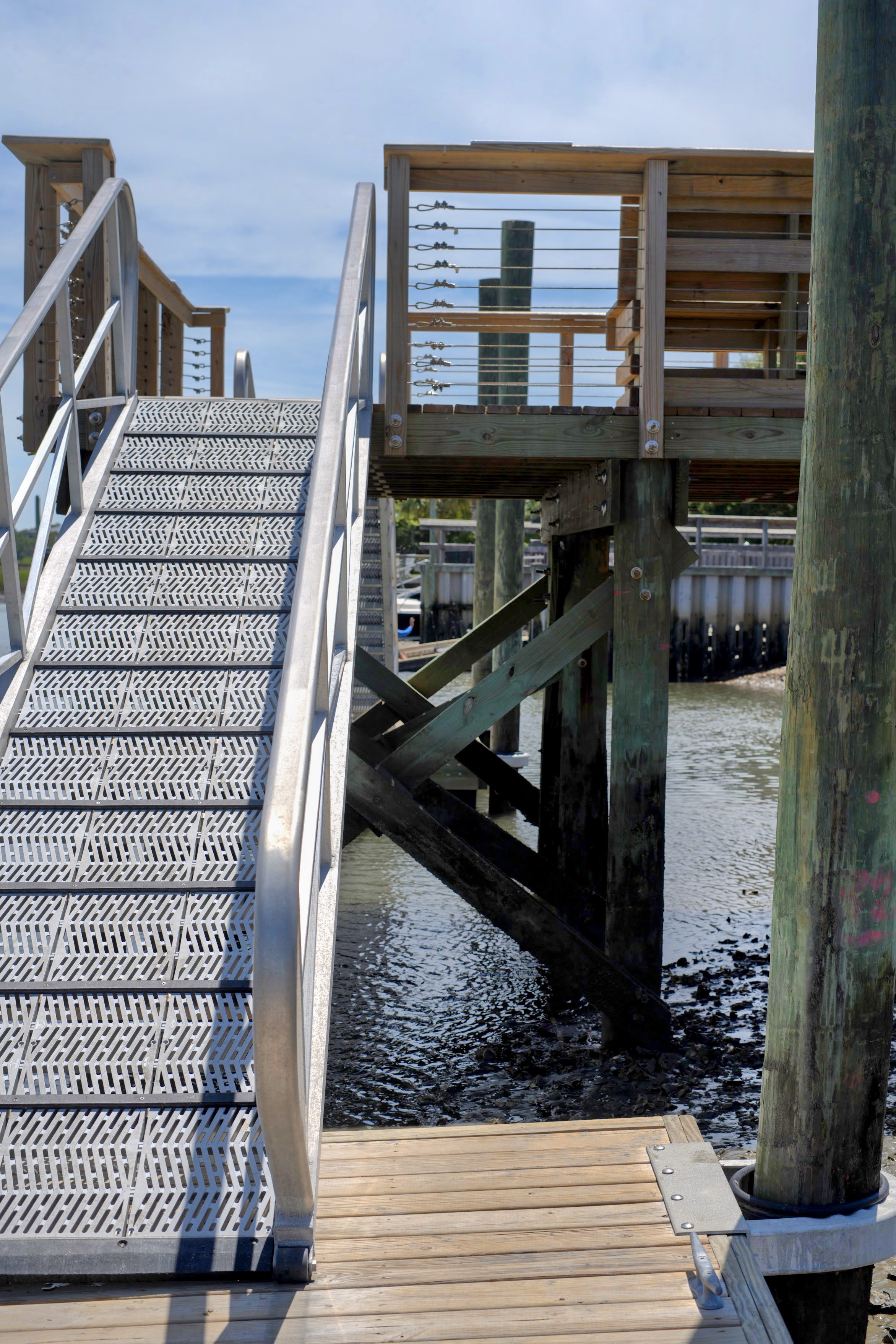 Metal gangway stairs leading up to an elevated wooden dock over marsh water in the Masonboro / Greenville Loop area of Wilmington, NC.