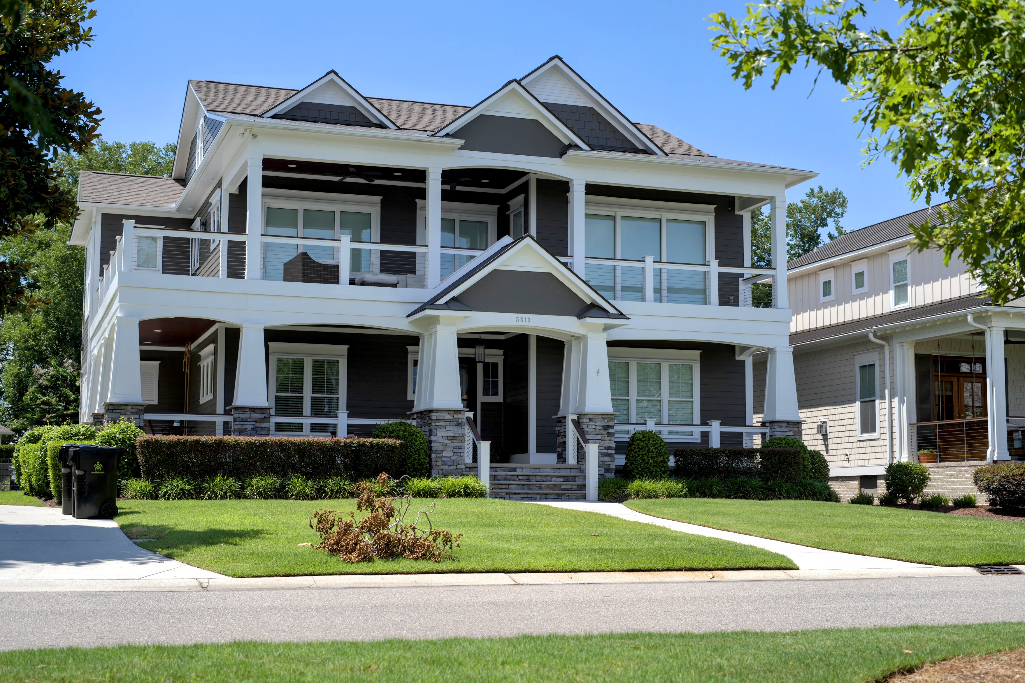 Craftsman-style coastal home with wraparound porches and a manicured lawn in Wrightsville Beach, NC.