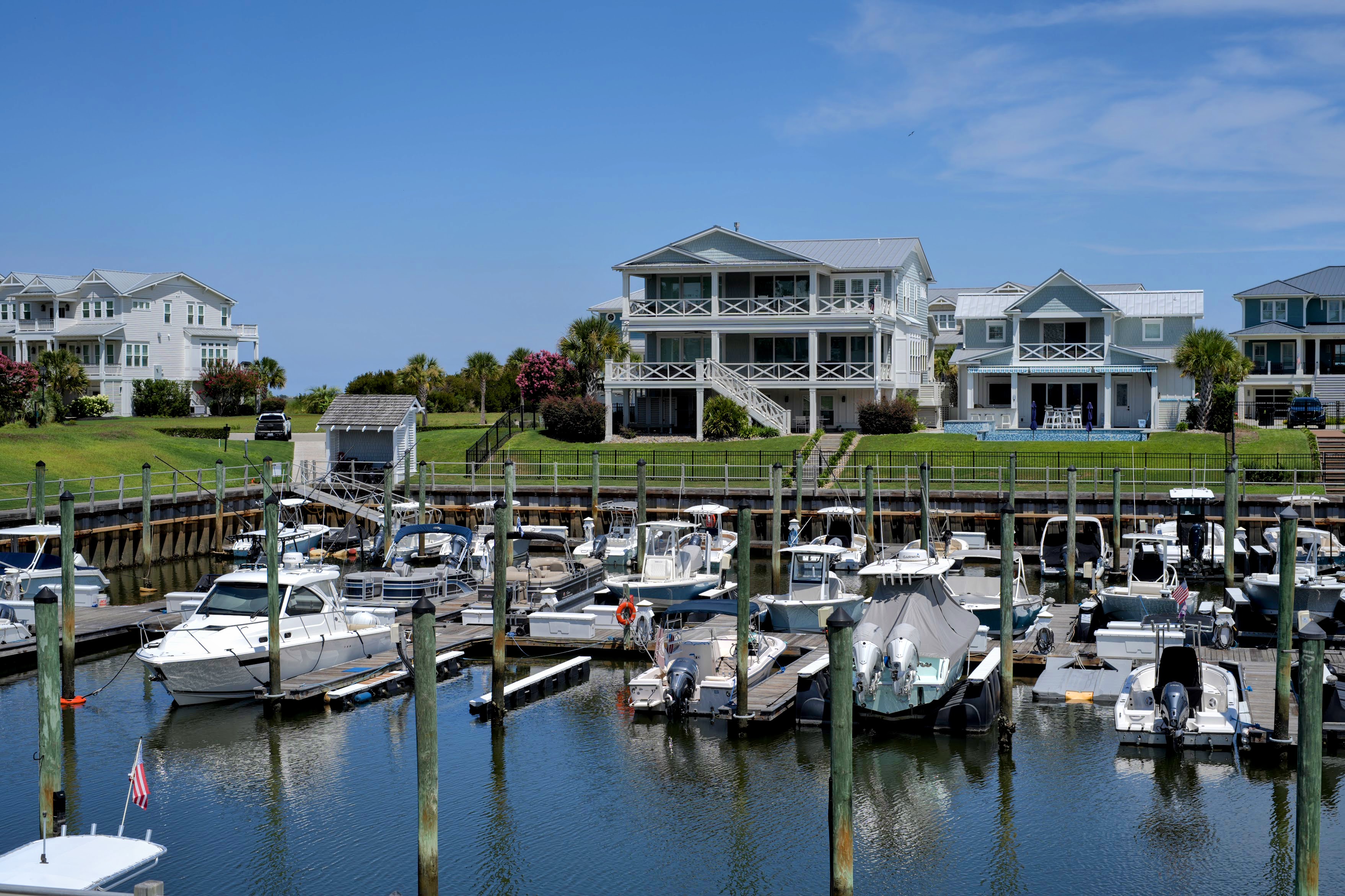Row of luxury waterfront homes overlooking a marina full of boats in Wrightsville Beach, NC.