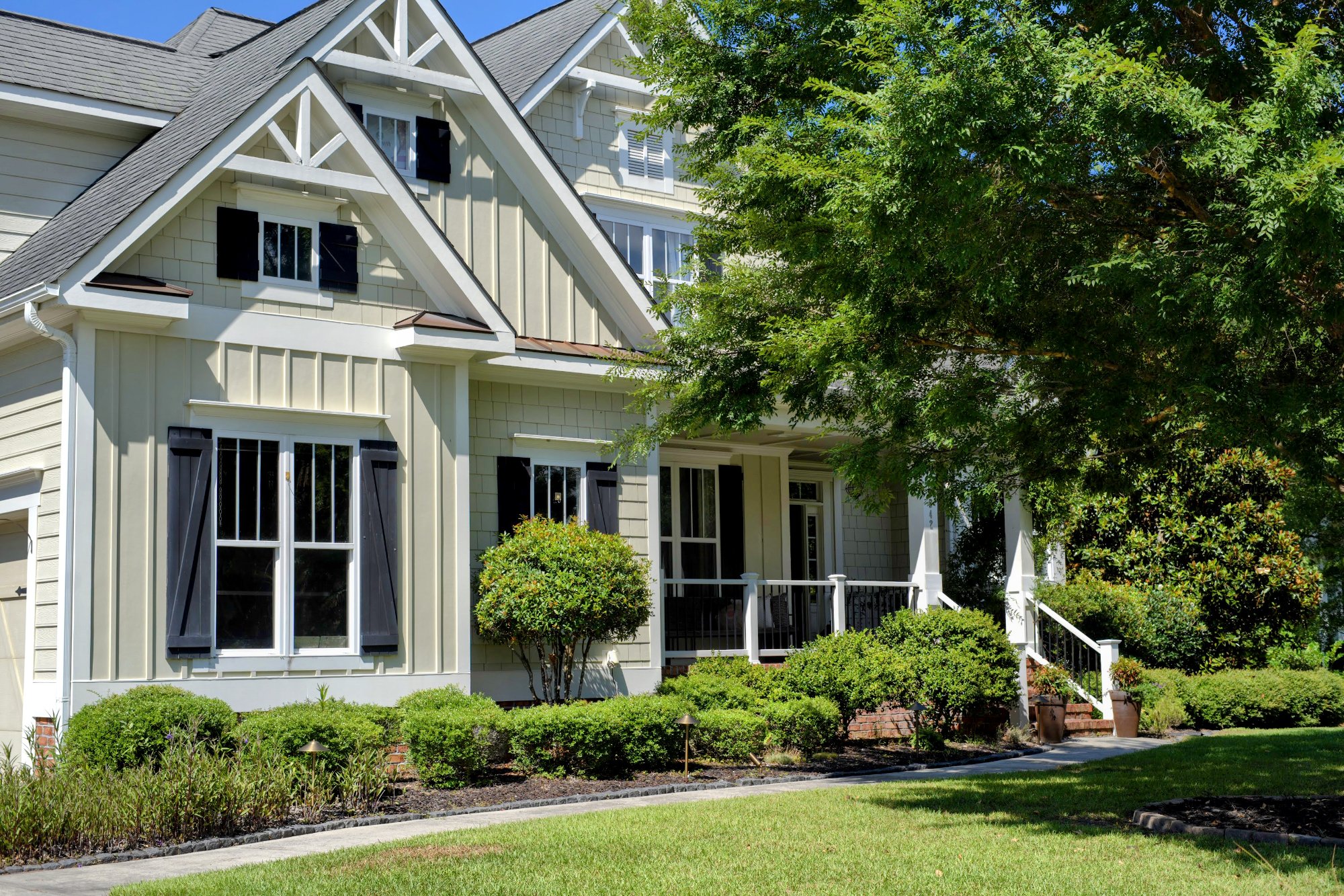 Coastal cottage-style home with board-and-batten siding, black shutters, and a landscaped front porch in Wrightsville Beach, NC.