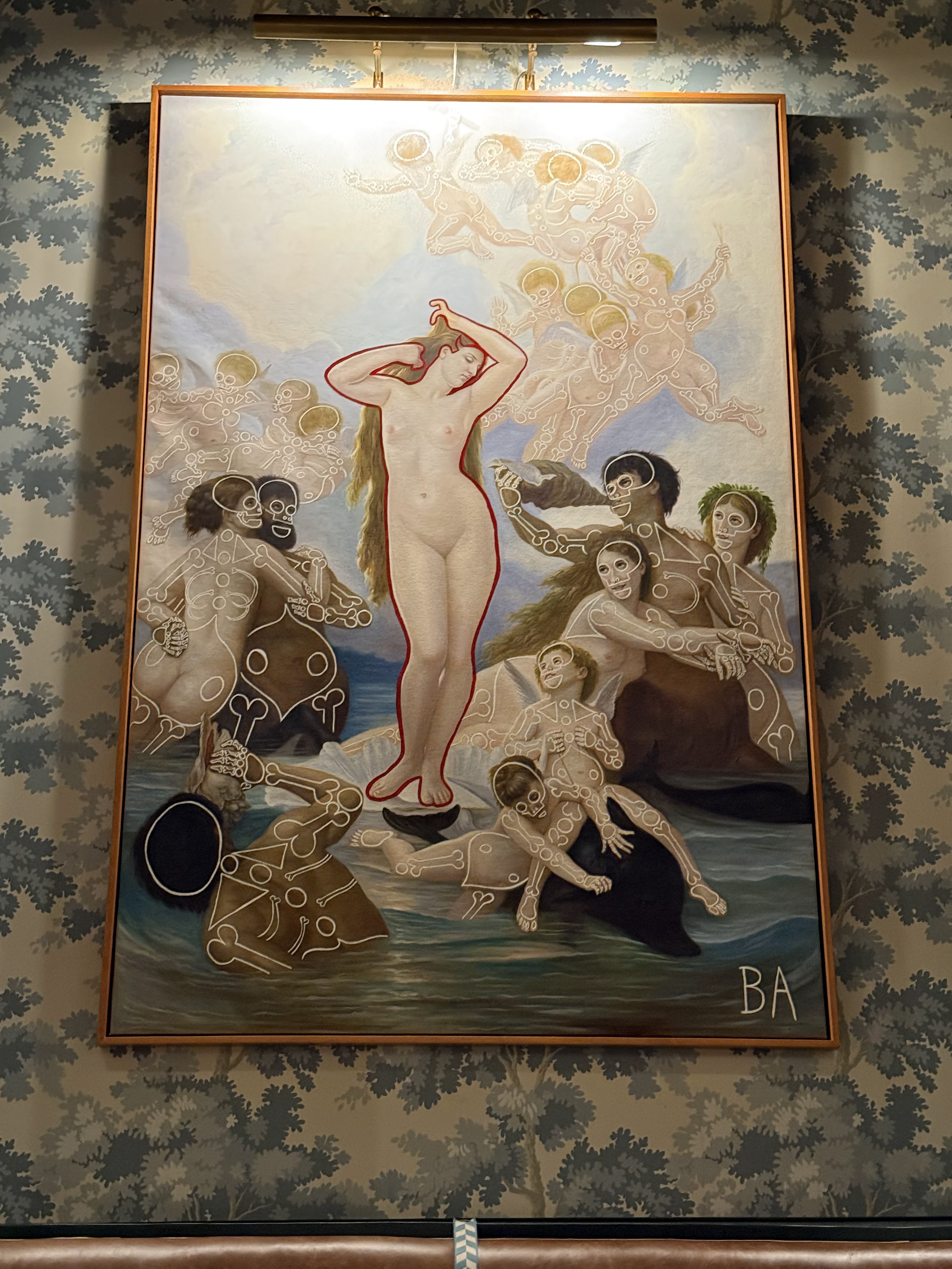 A large framed painting in a classical Birth of Venus style, lit from above and hung against botanical-patterned wallpaper over a leather banquette in the dining room at Olivero.