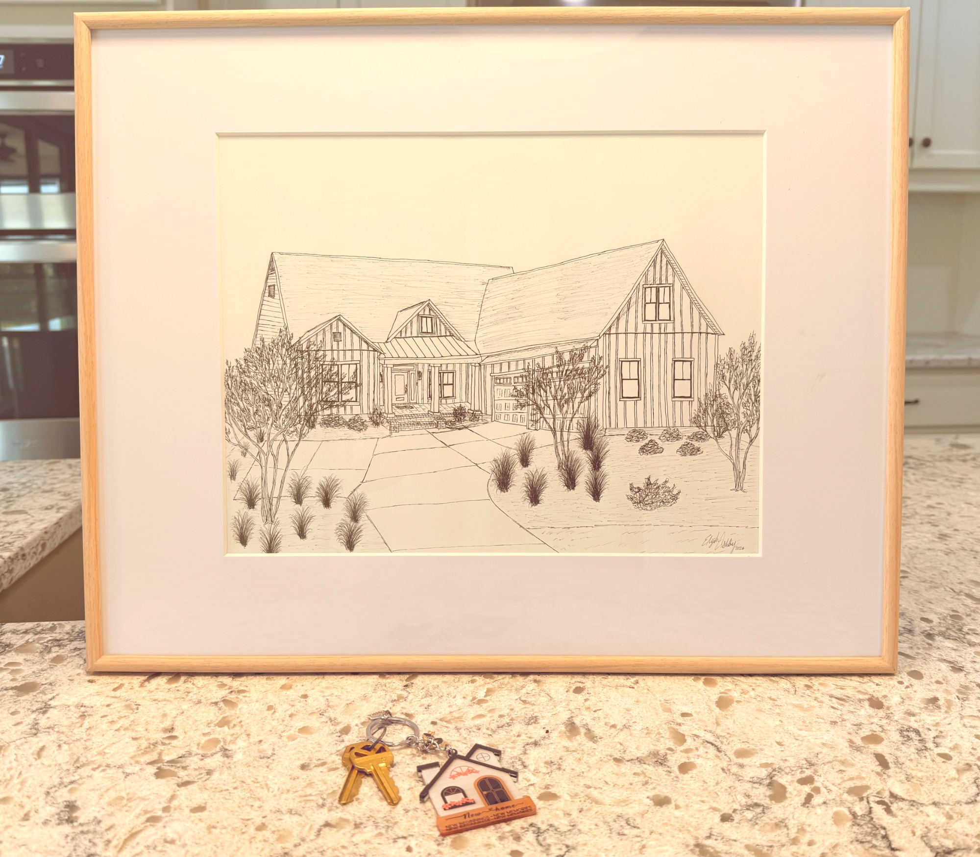Framed ink sketch of a modern farmhouse home on a kitchen counter with house keys, a personalized closing gift.