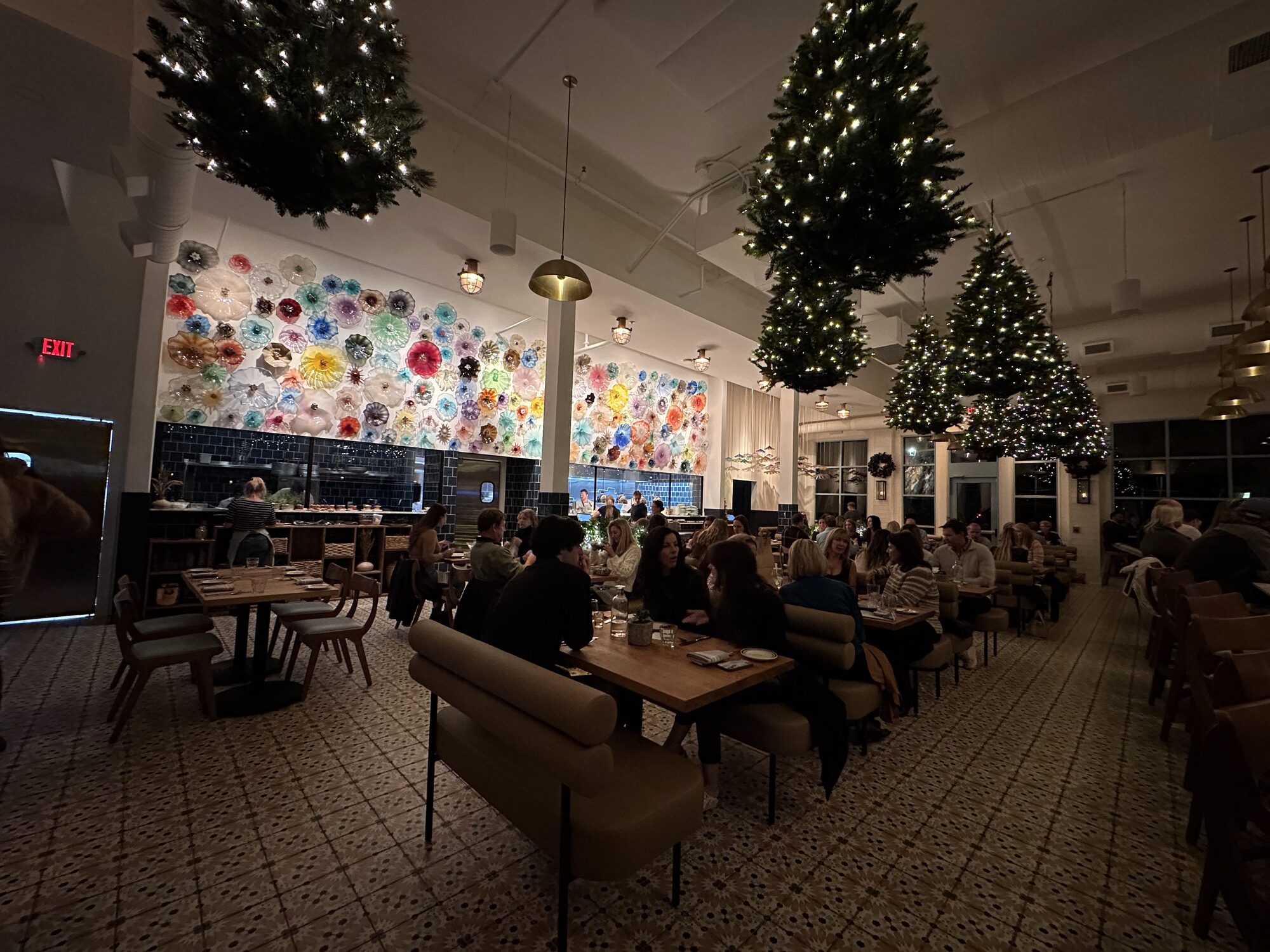 The dining room at Perla Raw Bar, with banquette seating and a wall of colorful floral artwork.