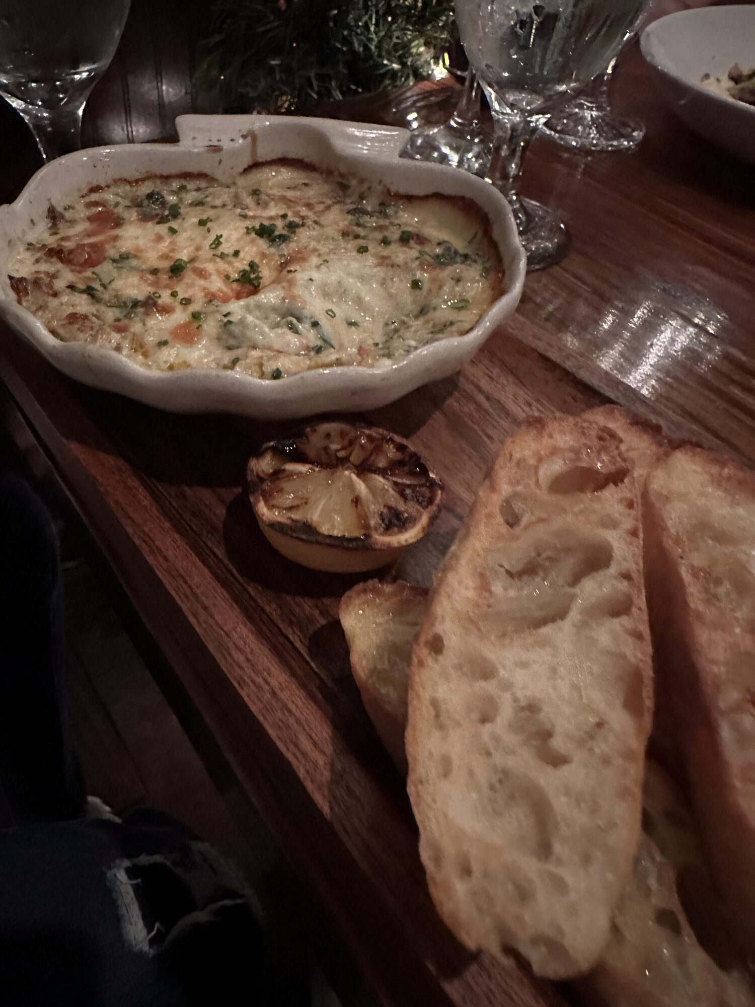 A baked cheese dip served on a wooden board with slices of grilled crusty bread at Circa 1922.